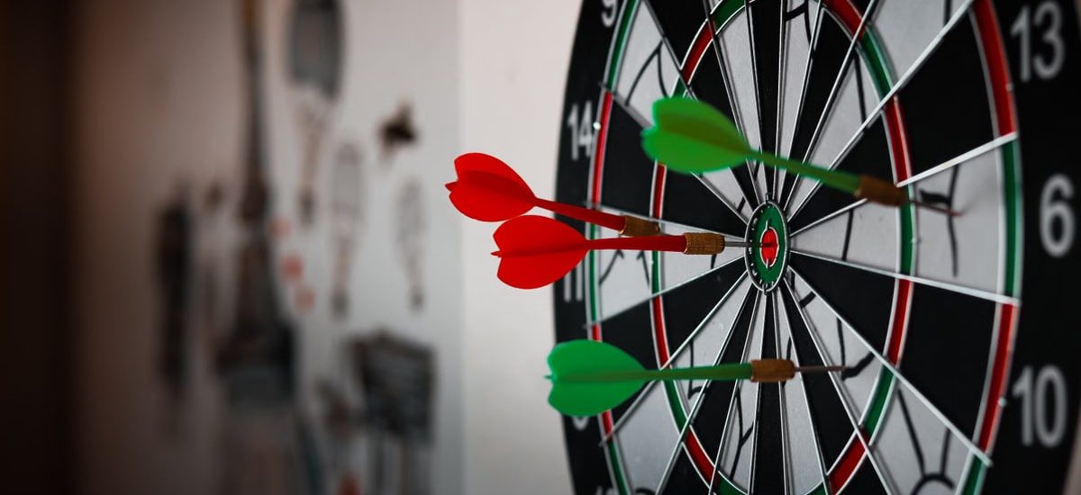 Close-up of a dartboard with multiple darts hitting the target, emphasizing precision and focus.